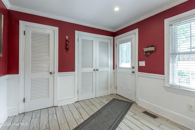 foyer featuring plenty of natural light, light wood finished floors, wainscoting, ornamental molding, and recessed lighting