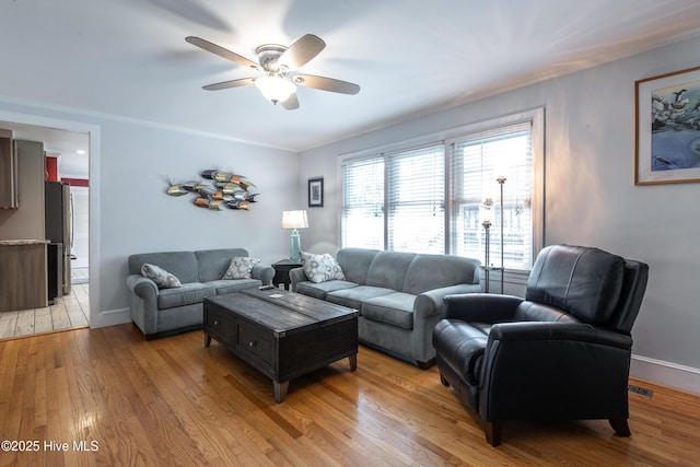 living area with a ceiling fan, light wood-style floors, baseboards, and ornamental molding