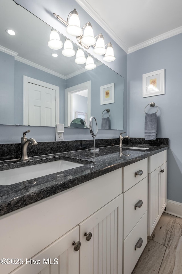 bathroom with crown molding, double vanity, wood finished floors, baseboards, and recessed lighting