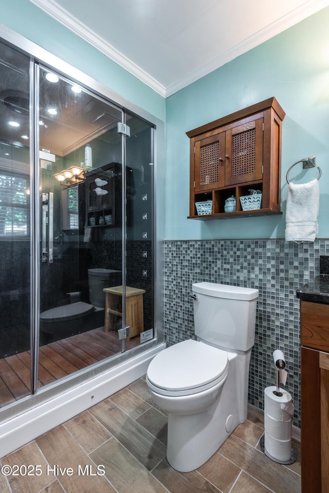 full bath with tile walls, toilet, ornamental molding, a stall shower, and vanity