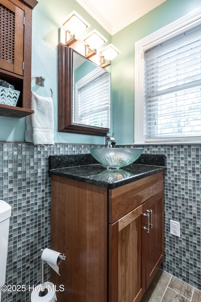 bathroom featuring tile walls, crown molding, toilet, and vanity