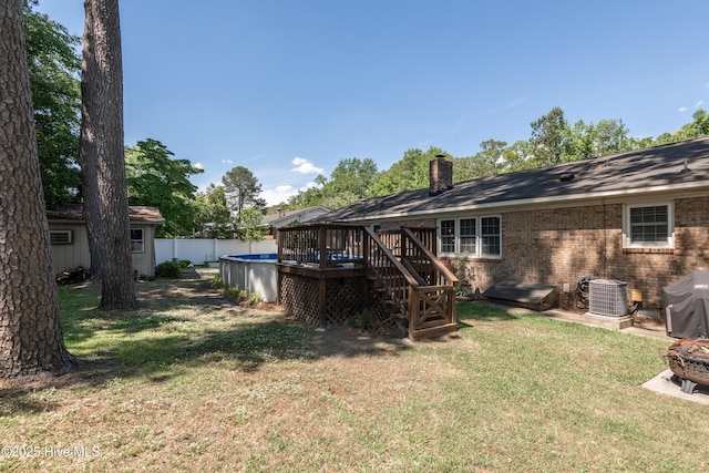 back of property with a wooden deck, central air condition unit, brick siding, and a chimney