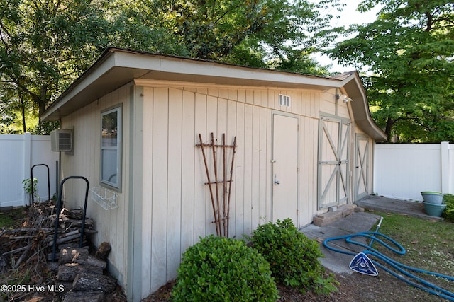 view of shed featuring fence and an AC wall unit
