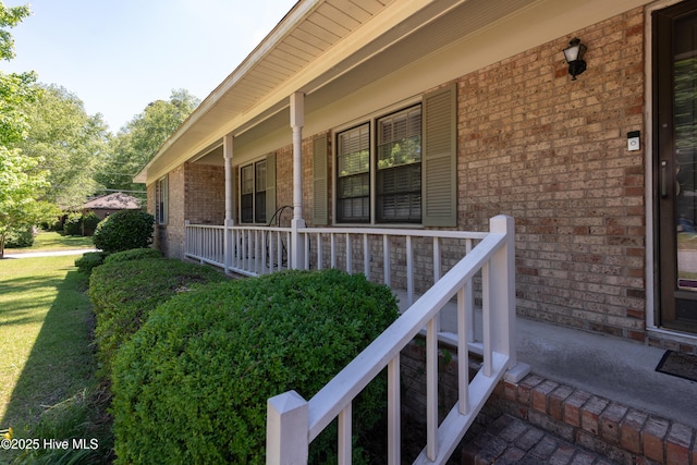 view of side of home with covered porch and brick siding