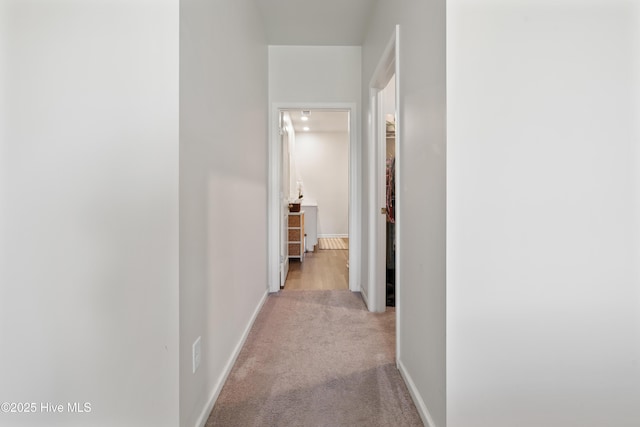 hallway with light colored carpet and baseboards