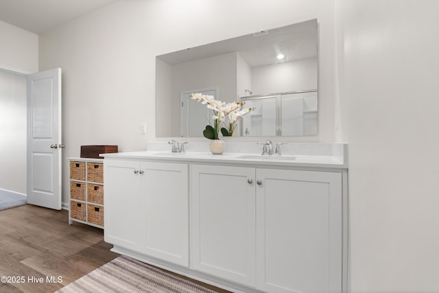 bathroom featuring wood finished floors, double vanity, and a shower stall