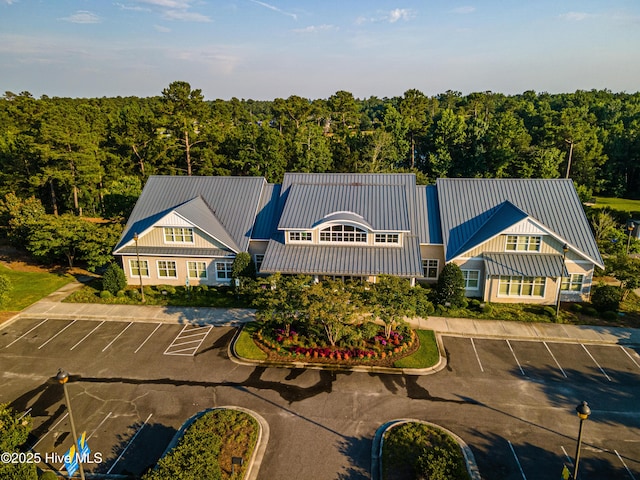 view of property with uncovered parking and a wooded view