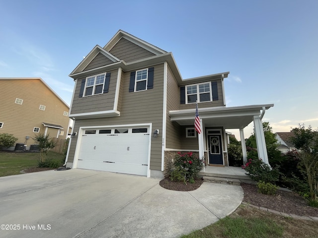 craftsman inspired home with covered porch, an attached garage, and concrete driveway