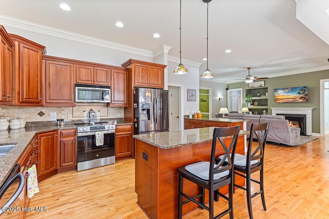 kitchen featuring light wood finished floors, stainless steel appliances, open floor plan, and brown cabinets