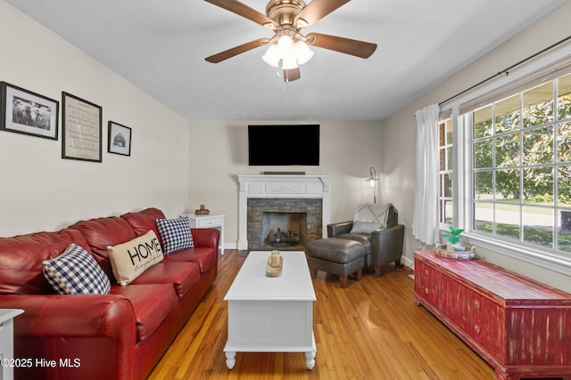 113 S Canal St, Whiteville, NC 28472 - living room featuring light wood-style floors, ceiling fan, a stone fireplace, and baseboards