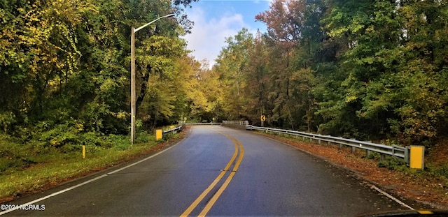 view of asphalt street with street lights and a view of trees