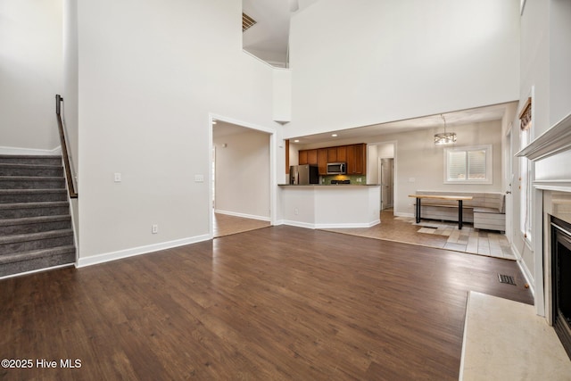 870 Wine Cellar Cir, Wilmington, NC 28411 - unfurnished living room with stairway, dark wood-style floors, a fireplace with flush hearth, baseboards, and a towering ceiling
