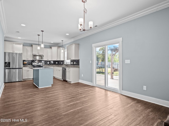 kitchen featuring appliances with stainless steel finishes, crown molding, a chandelier, backsplash, and baseboards