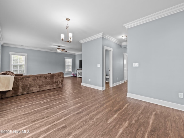 unfurnished living room with a chandelier, crown molding, plenty of natural light, baseboards, and wood finished floors