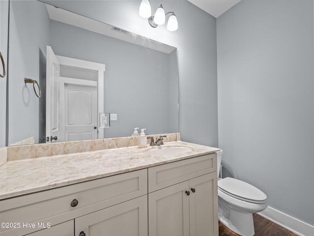 bathroom featuring wood finished floors, baseboards, toilet, and vanity