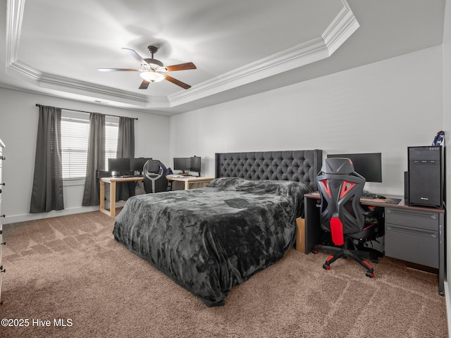 carpeted bedroom featuring a tray ceiling, ornamental molding, a desk, and ceiling fan
