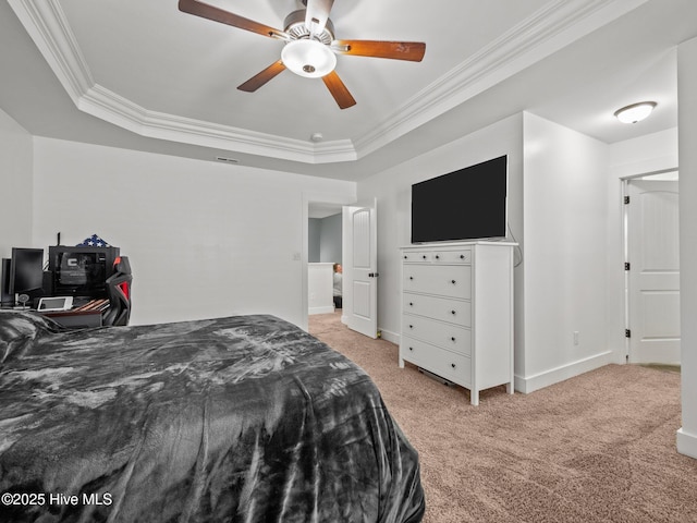 bedroom featuring light carpet, crown molding, a tray ceiling, baseboards, and ceiling fan