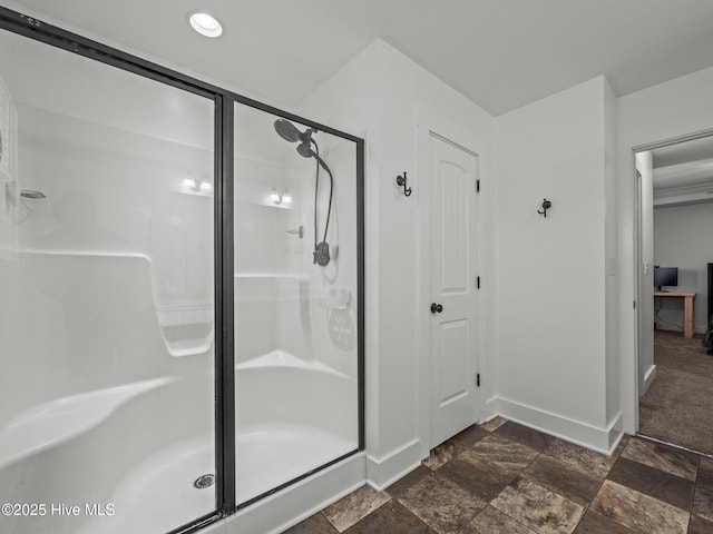 bathroom with a shower stall, stone finish floors, and baseboards