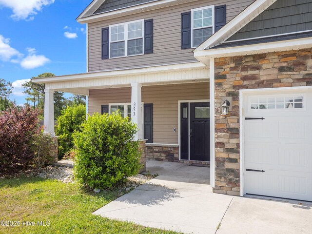 entrance to property with stone siding, covered porch, and a garage