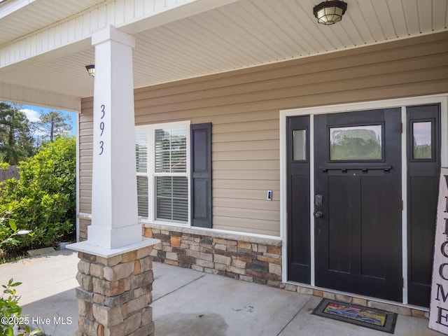 view of exterior entry with covered porch and stone siding