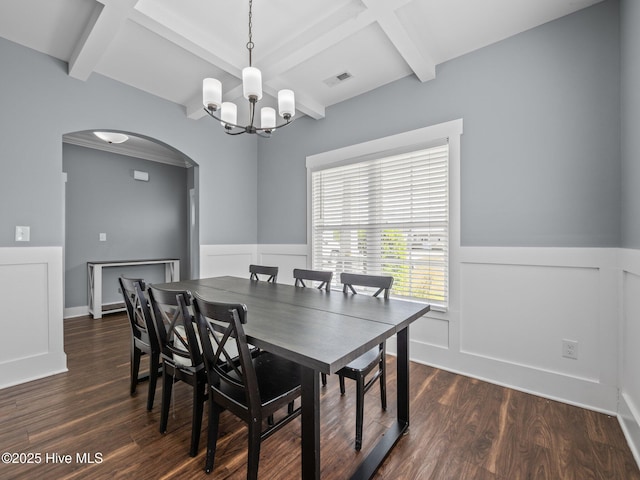 dining space with arched walkways, wainscoting, dark wood-style flooring, beamed ceiling, and a chandelier