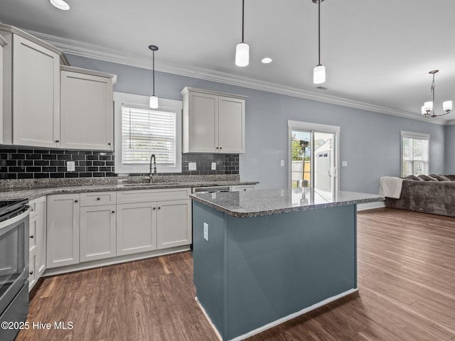kitchen with a sink, dark wood finished floors, ornamental molding, stainless steel range with electric cooktop, and open floor plan