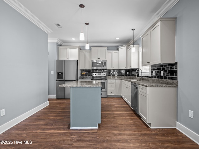 kitchen featuring stainless steel appliances, crown molding, baseboards, a kitchen island, and backsplash