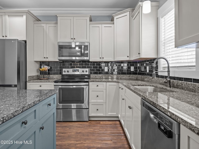 kitchen featuring stainless steel appliances, a sink, dark stone counters, backsplash, and crown molding