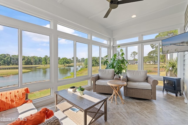sunroom featuring a wood stove, tile patterned flooring, and view of scattered trees