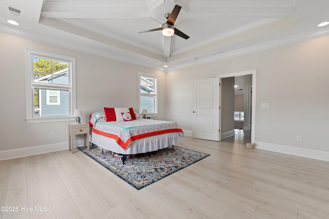 bedroom with a tray ceiling, multiple windows, crown molding, light wood-style floors, and baseboards