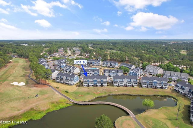 aerial overview of property's location with a large body of water, a golf course, nearby suburban area, and a forest
