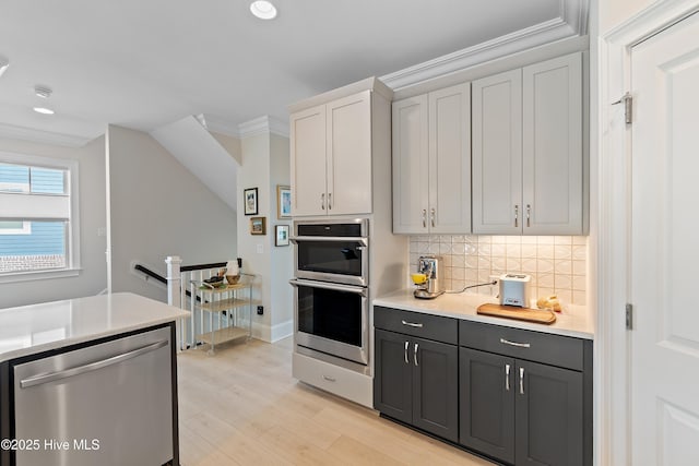 kitchen with stainless steel appliances, light countertops, ornamental molding, light wood finished floors, and recessed lighting