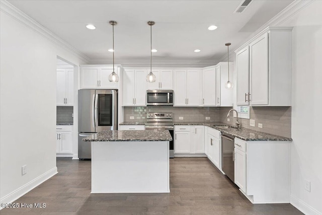 107 Meadowview Pl, Whispering Pines, NC 28327 - kitchen featuring appliances with stainless steel finishes, dark stone counters, a center island, white cabinetry, and crown molding