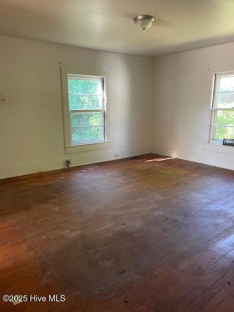 empty room featuring dark wood-type flooring and baseboards