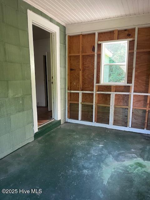 spare room featuring concrete flooring and concrete block wall