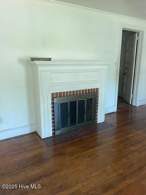 detailed view of a brick fireplace, wood finished floors, baseboards, and crown molding