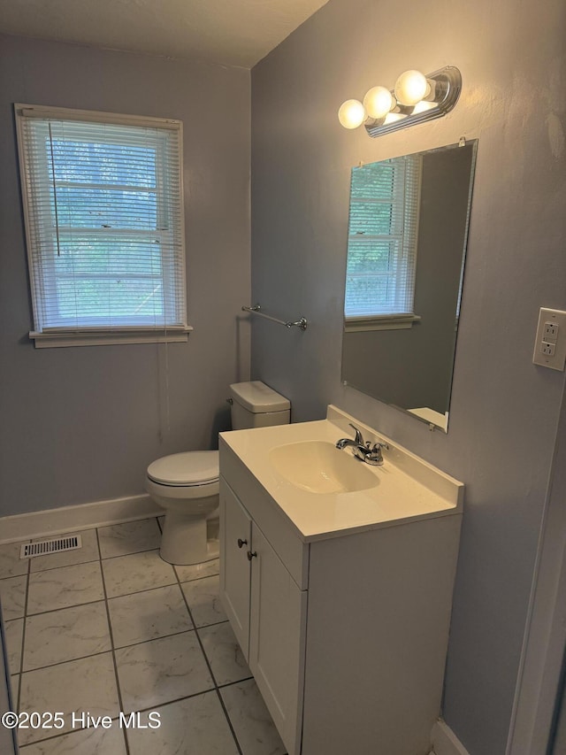 half bath with marble look tiles, toilet, vanity, and baseboards