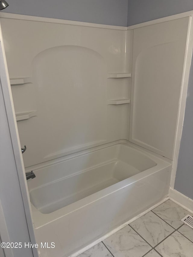full bath featuring marble look tiles, bathing tub / shower combination, and baseboards