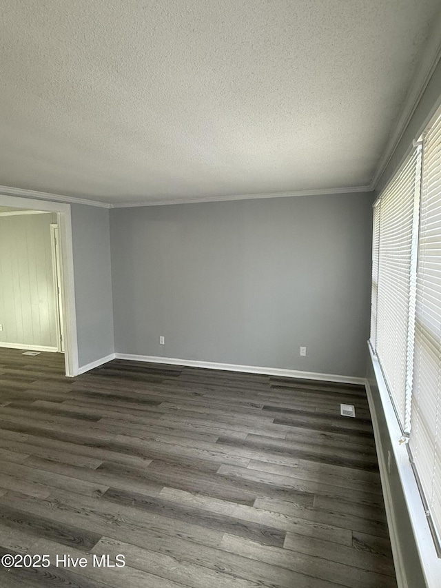 spare room with dark wood finished floors, ornamental molding, a textured ceiling, and baseboards