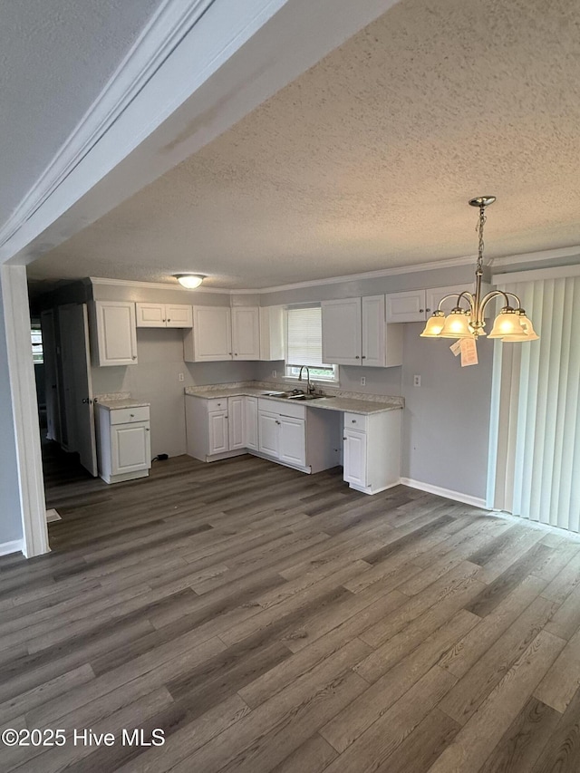 kitchen with a textured ceiling, white cabinets, a sink, dark wood finished floors, and light countertops