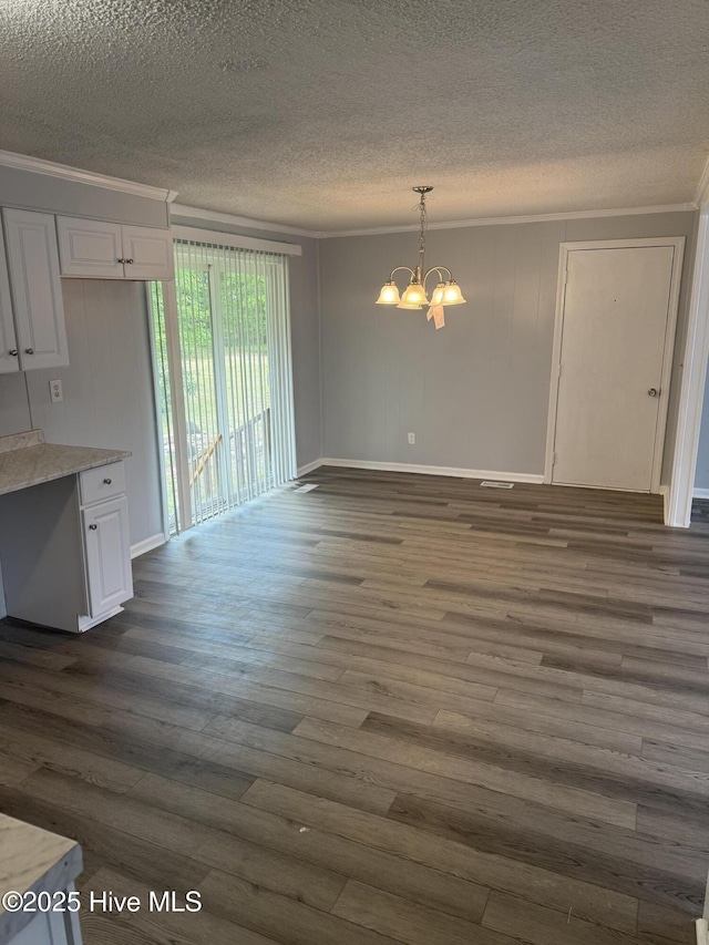unfurnished dining area with crown molding, a chandelier, dark wood finished floors, a textured ceiling, and baseboards