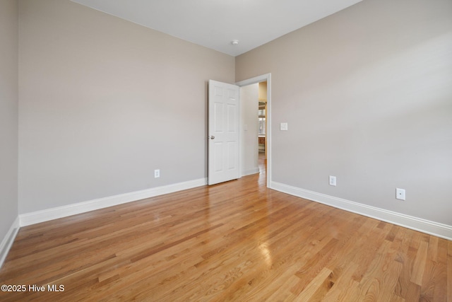 unfurnished room with baseboards and light wood-style flooring