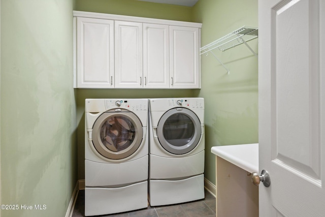 clothes washing area with cabinet space, washing machine and dryer, and baseboards