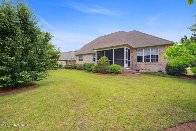 rear view of house featuring brick siding, a sunroom, a lawn, crawl space, and a shingled roof