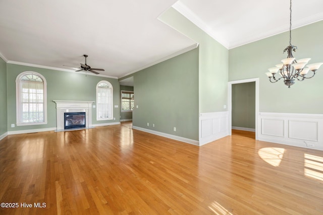unfurnished living room featuring crown molding, a chandelier, ceiling fan, light wood finished floors, and a glass covered fireplace