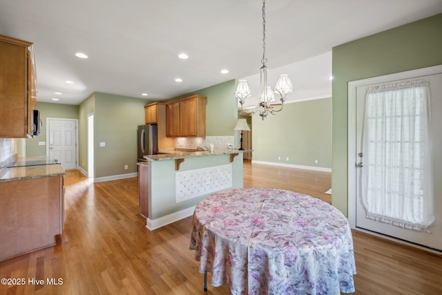 kitchen with appliances with stainless steel finishes, a chandelier, decorative backsplash, light stone countertops, and recessed lighting