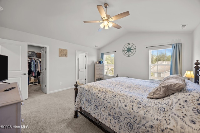 bedroom with vaulted ceiling, light colored carpet, a walk in closet, baseboards, and ceiling fan