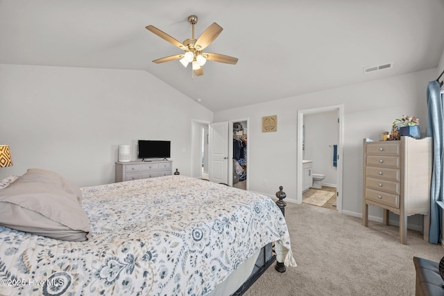 bedroom featuring lofted ceiling, a walk in closet, carpet flooring, baseboards, and ceiling fan