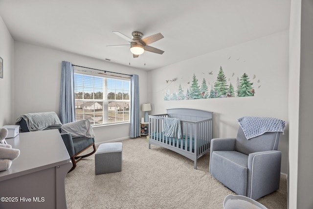 carpeted bedroom featuring baseboards, a ceiling fan, and a nursery area