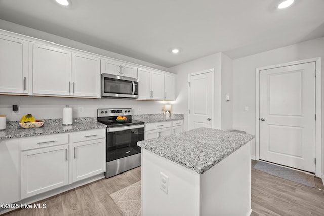 kitchen featuring stainless steel appliances, light wood finished floors, white cabinetry, a kitchen island, and recessed lighting